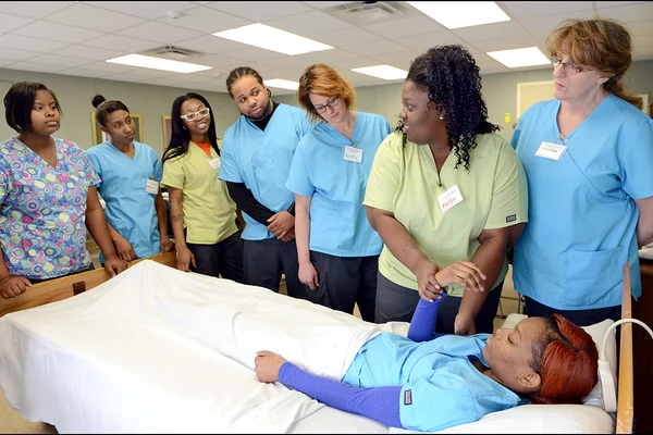 Nurse assistant students watching demonstration at patient bed