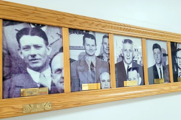 A series of black and white portraits of men on a wall