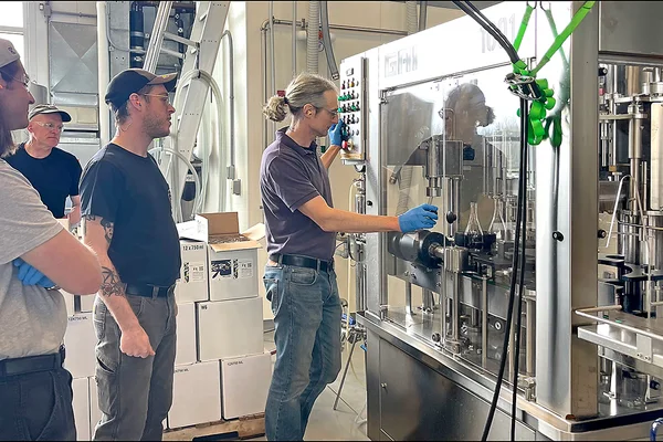 Instructor showing 3 students a wine bottling machine
