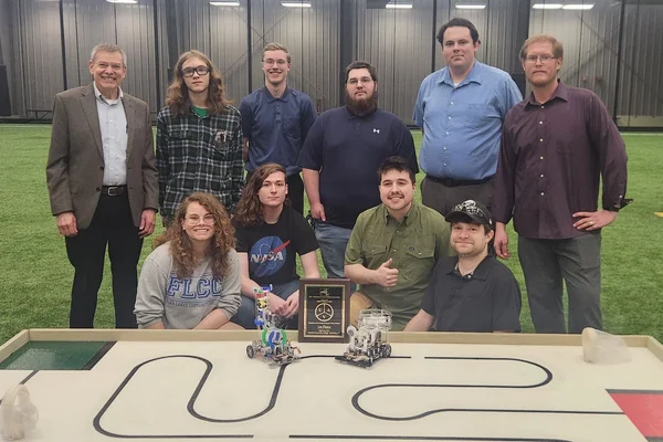 A group of eight engineering students and two advisors posing with robots they built