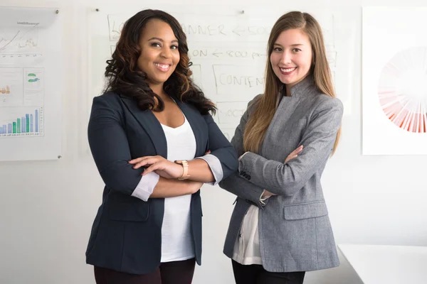 Two employees in a business setting with marketing charts and graphs displayed on the walls.