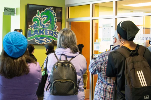 Group of people viewing an unveiling of a LEGO mosaic wall art.