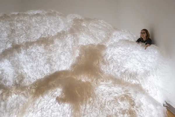 woman behind a large cloudlike art installation