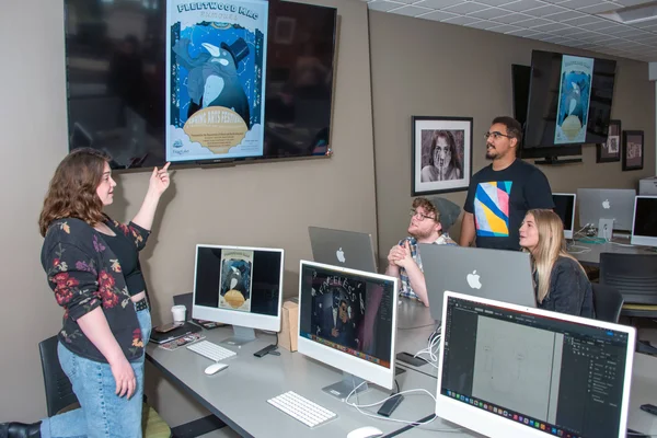 Students in Graphic Arts lab reviewing designs for the Spring Arts Festival competition.