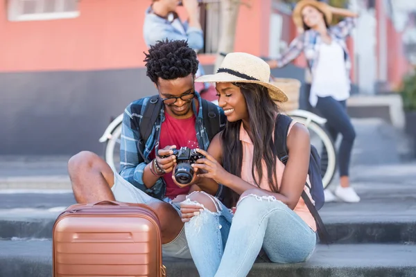 Two tourists exploring new places together pause momentarily to review photos on a camera.