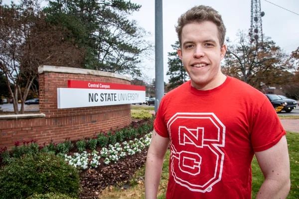 Male student in front of NC State sign