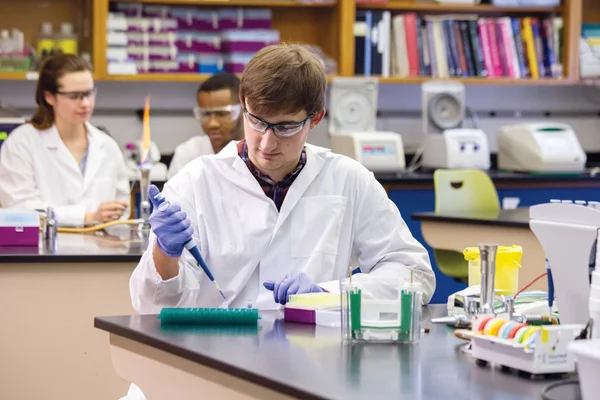Student in biotechnology lab using a pipette.