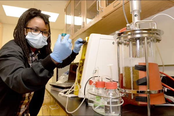 Woman in science lab, inspecting vial