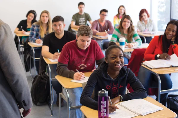 A classroom full of students, taking notes and engaging in class discussion.