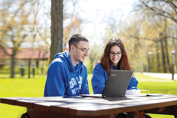 Two students streaming a club event on their laptop.