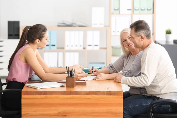 A paralegal works with two clients in a law office, reviewing documents.