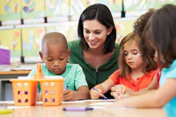 A teaching assistant helping 3 elementary students with an art project.