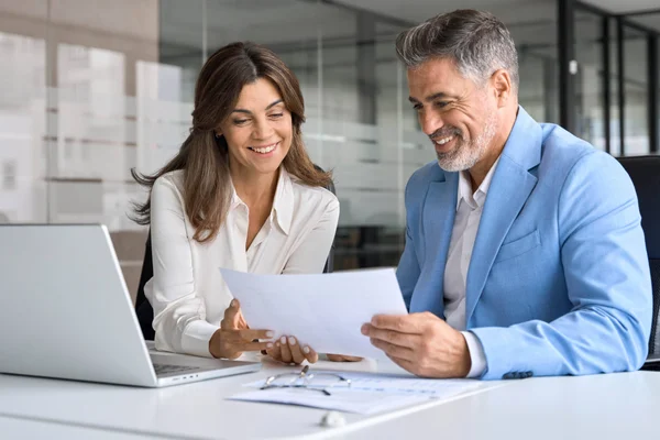 Staff work together in a business setting at a laptop.