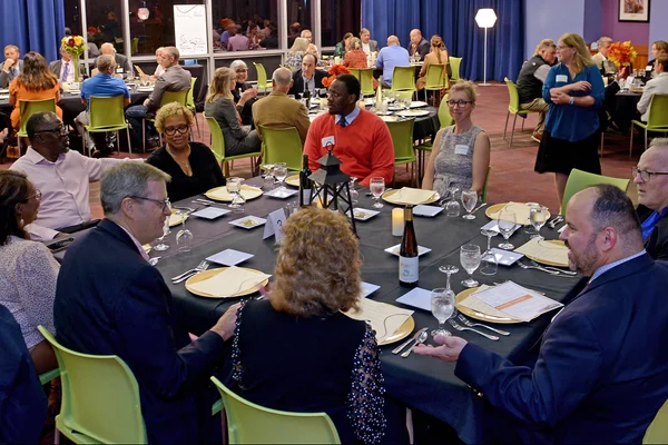 FLCC employees gathered around tables in a room, enjoying a meal together.