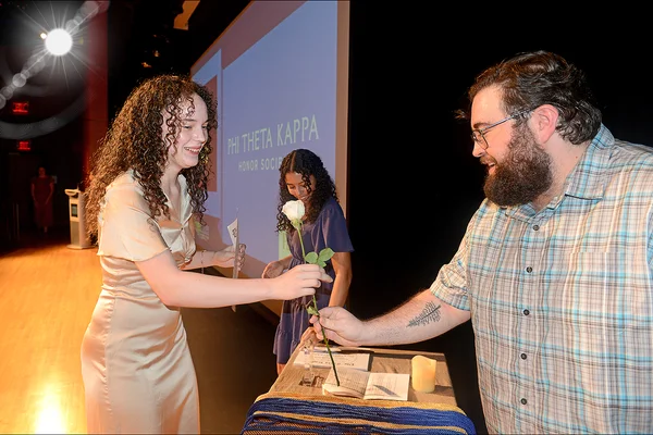 Man handing white flower to a woman at a ceremony