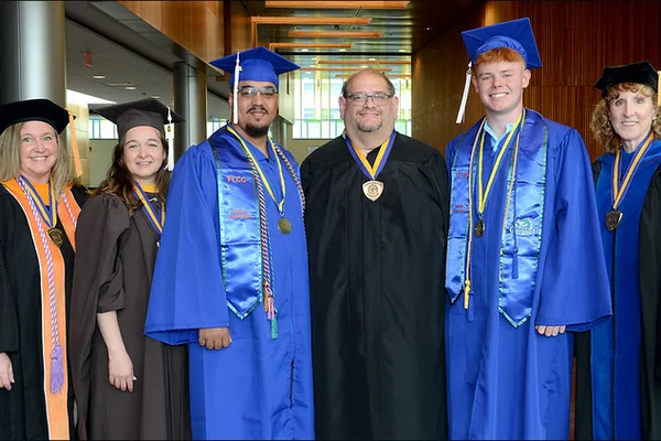 Three men and women posing in academic regalia