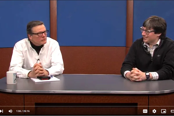 Christopher Parker, Jeff Dugan sitting behind TV studio desk