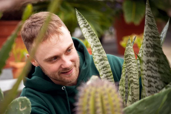 A young man carefully examines a white and green leafed plant in the Finger Lakes Community College greenhouse.