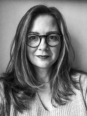black and white headshot of a woman with long hair and glasses