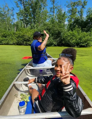 Student from Urban League of Rochester summer camp posing for a photo while riding in a canoe at the FLCC Muller Field Station.