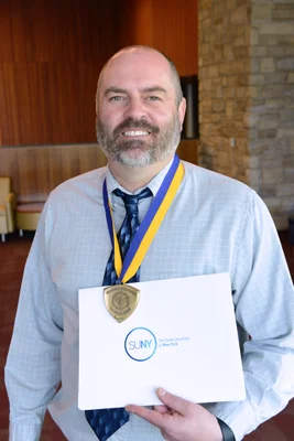 Man wearing medal holding certificate