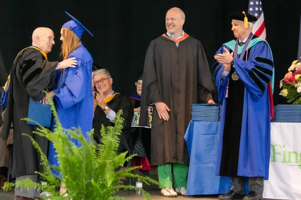 Older man greets granddaughter on stage at graduation