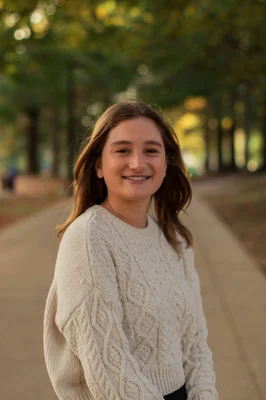 Portrait photo of a woman in a white sweater outdoors