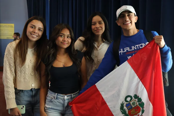 Four students pose for a photo with a Peruvian flag at the FLCC Food for Thought event in October 2024.