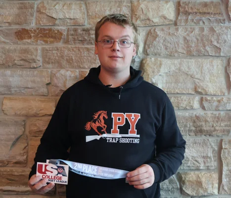 FLCC student Mason Bush posing for a photo while holding an award for clay target shooting.