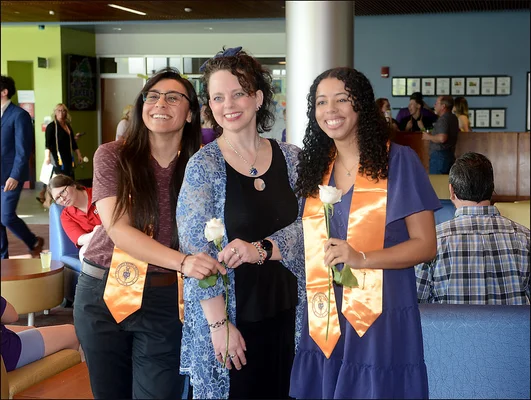 Three woman posing, two wearing honor society stoles