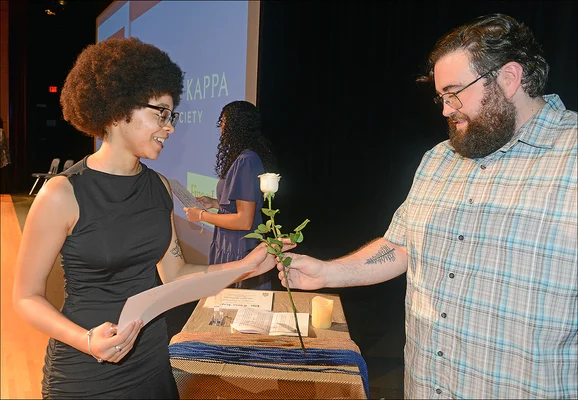 Man hands women white rose at ceremony
