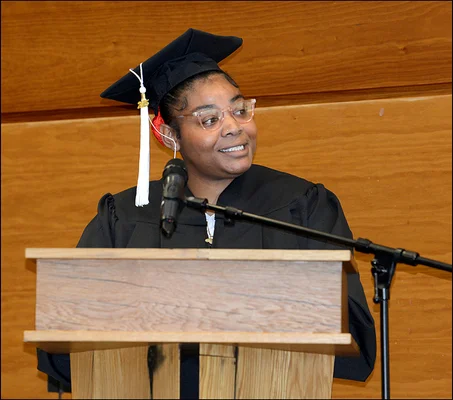 Woman in cap and gown speaking at podium