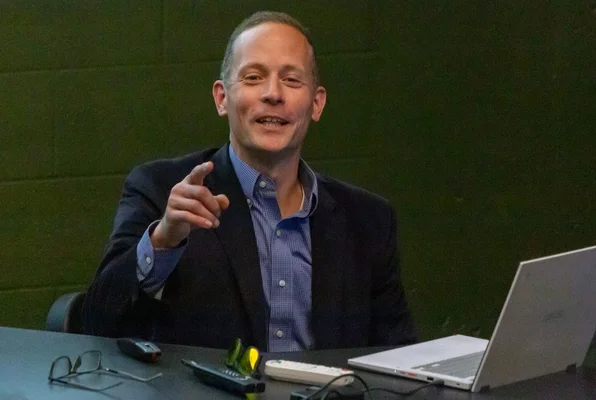 Man speaking while seated at desk and gesturing