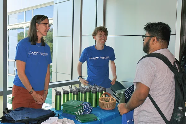 A man and women at a table with SUNY ASAP swag talk to a student