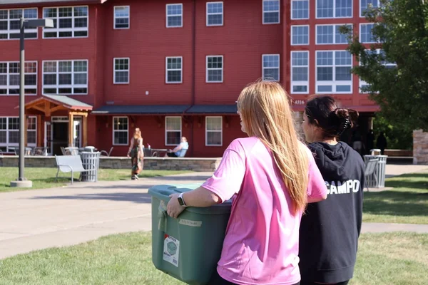 Two students carrying items into the Suites.
