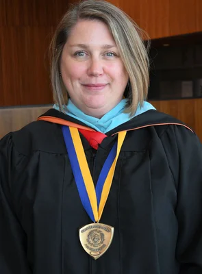 Head and shoulders photo of woman in academic regalia wearing a medal