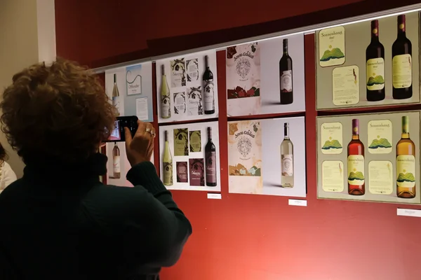 A guest at the fall 2025 wine label design competition taking photos of the design boards that were presented.